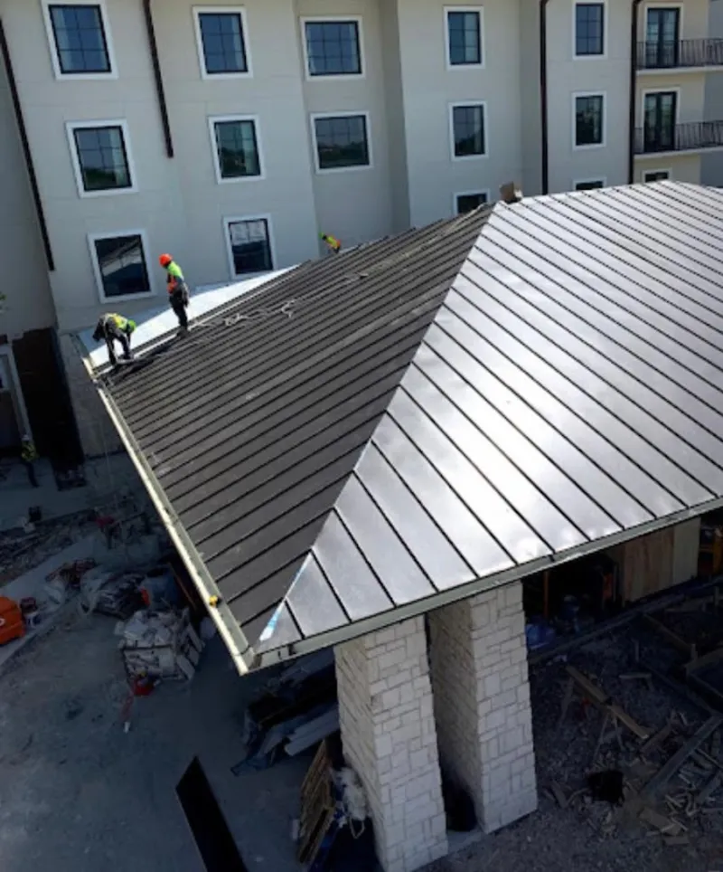 Crew installing standing seam metal roof panels on a commercial project in Moundsville